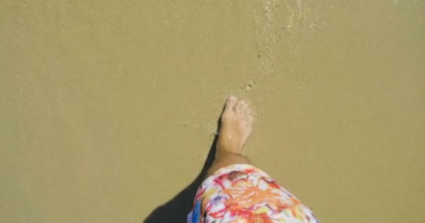 晒黑的腿上的一个男人 在游泳五颜六色的短裤 背景的海棕色的沙子 海洋清洁空气 顶视图 — 图库视频影像