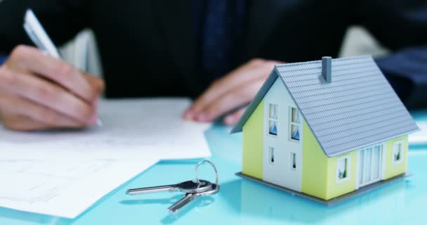 Miete oder Kauf des Hauses. Die Hände eines Versicherers oder Immobilienmaklers, der ein Haus mit Hausschlüsseln vorzeigt .