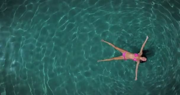 透明な海の水に浮かぶ女性の空撮ビデオ — ストック動画