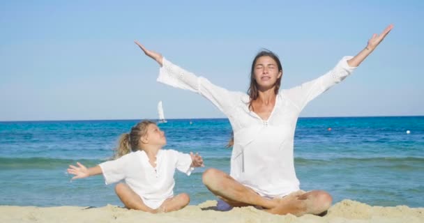 母と娘 ヨガに取り組んで海で白服が笑っている 青い海の水の背景 母と娘の友情 休日の概念 — ストック動画