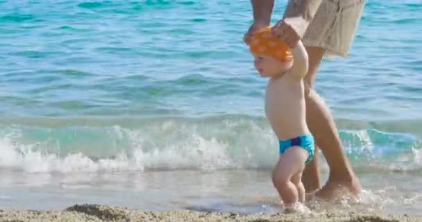 在假期里 妈妈在海滩上对他的小宝宝迈出了第一步 新生儿一步一步学会走路 — 图库视频影像