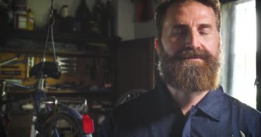 Portre yakışıklı Kafkas sakallı adam atölyede, poz ve kolları ile kameraya bakarak geçti 