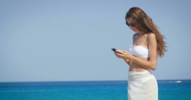 deniz güneş gözlüğü ve mayo giyen ve cep telefonu tarama kadın video 