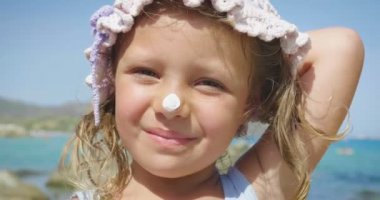 Denizde, panama, güneş koruma kremi, arka plan mavi deniz suyu ve kayalar gülümseyen şirin eğleniyor güzel küçük kız portresi. Konsept: çocuk, çocukluk, yaz, özgürlük, çocuk, Bebek