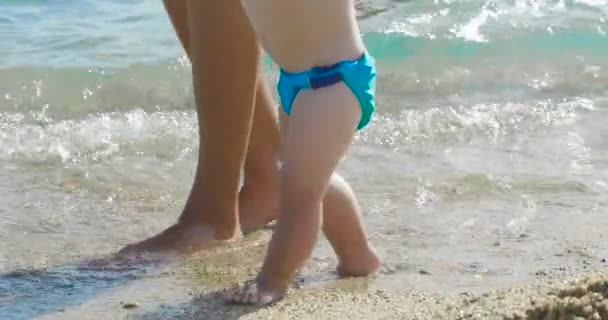 在假期里 妈妈在海滩上对他的小宝宝迈出了第一步 新生儿一步一步学会走路 — 图库视频影像