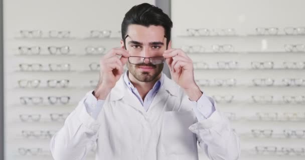 Повільне Відео Чоловіка Окулярах Оптичному Центрі Дивиться Камеру Посміхається Схрещеними — стокове відео