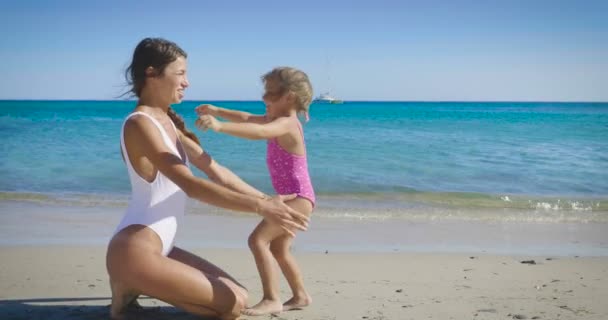 最高の瞬間に幼い娘を持つ母太陽の保護クリーム 海と砂の背景 サングラス 海に再生されます コンセプト ライフ スタイル — ストック動画