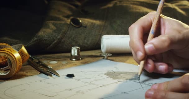 Mouvement lent d'une main d'un jeune tailleur qui dessine avec un crayon dans son étude des vies à produire pour la nouvelle collection 