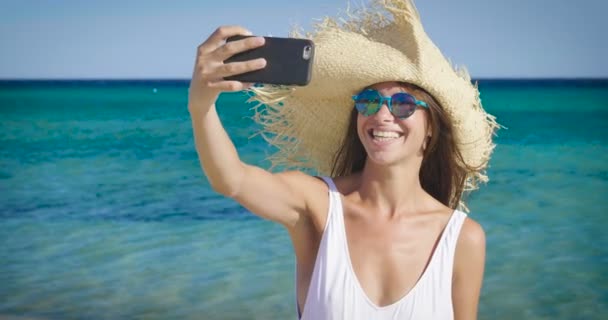 海で携帯電話を保持しているとカメラに舌を示す面白い女性のビデオ — ストック動画