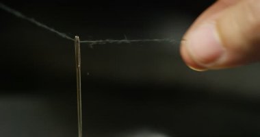 Ağır çekim iğne iplik el koyan genç bir terzi el giyim bir parça oluşturmak için kumaş dikmek