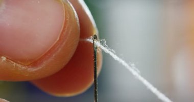 Ağır çekim iğne iplik el koyan genç bir terzi el giyim bir parça oluşturmak için kumaş dikmek