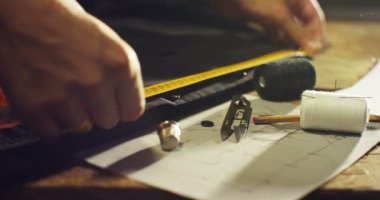 Ağır çekim el dikiş için bant ile doku ölçümleri yapan genç bir terzi