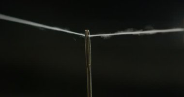 Ağır çekim iğne iplik el koyan genç bir terzi el giyim bir parça oluşturmak için kumaş dikmek