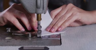 Yetenekli bir terzi dikiş makinesi ile İtalyan geleneğe göre beyaz bir kumaş dikiş bir giysi moda giyim yapmak için bir kalite kumaş diker. terzilik kavramı, moda, gelenek