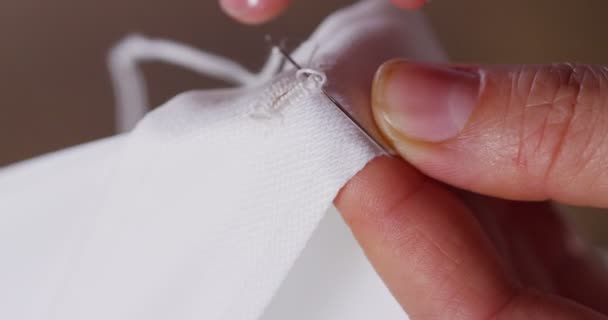 テーラーの伝統によると仕立ての白い布を縫製若い女性の裁縫師の手 洋裁用途は完全に針し 伝統的な概念 スタイルとファッションを縫う糸 — ストック動画