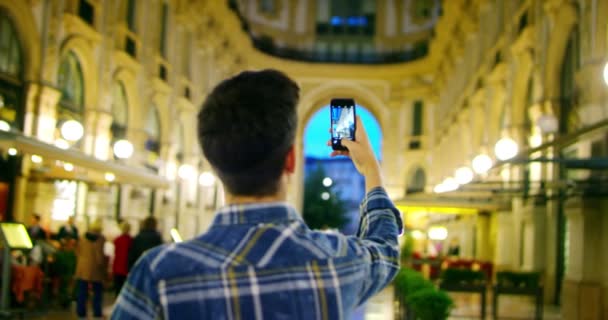 男人在城市里看夜晚 意大利英俊的年轻商人用电话微笑快乐穿着蓝色衬衫 城市男性 短信发短信的人在城市应用程序使用手机 — 图库视频影像