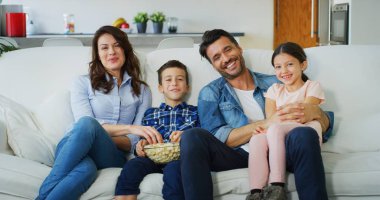 Portrait of happy family watching TV on sofa in living room in slow motion. Concept of family entertainment, education, technology. clipart