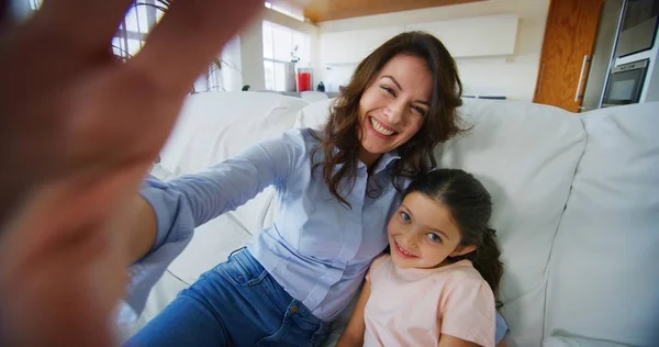 Portrait of happy mother and daughter taking selfie in living room in slow motion. Concept of communication, connection, technology, lifestyle, social, family.