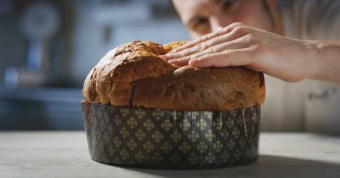 Şef yumuşaklığı anlamak için eliyle dokunarak onun İtalyan panettone kalitesini kontrol eder