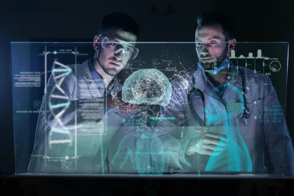 A couple of doctors or scientist analyze the patient\'s medical situation by checking on a glass monitor with a futuristic holography. Concept of: medicine, doctors, future, holography.