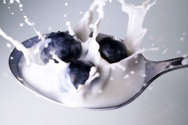 Bir bluebarries bir kaşık sütle dolu düşme, yakın çekim. Konsept: Kahvaltı, diyet, yaz