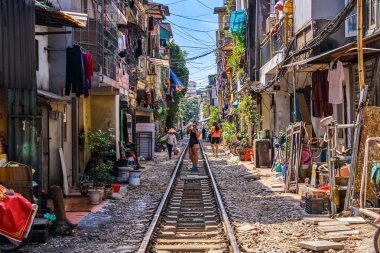 Kadın, Hanoi şehri demiryolu perspektifinin resmini yapıyor. Vietnam 'da evleri olan dar sokaklar boyunca koşuyor.