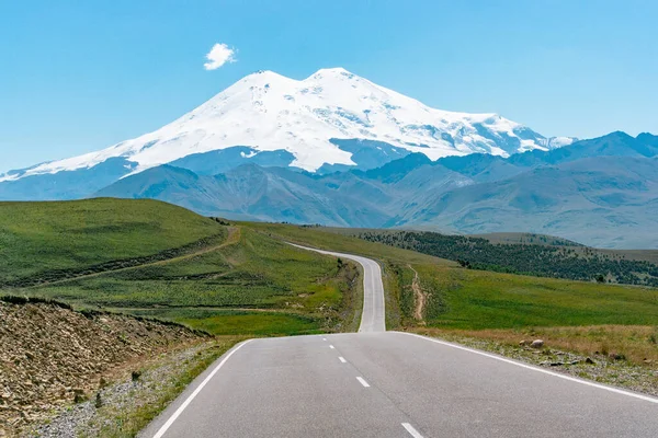 Avrupa 'nın en yüksek zirvesinin manzarası, güneşli bir yaz gününde yeşil tepeli Elbrus Dağı.