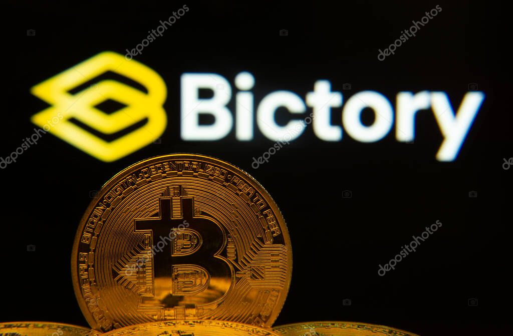 Dhaka, Bangladesh- 09 Sep 2025: Close-up of Bitcoin coins with the Bictory logo visible on a screen in the background.