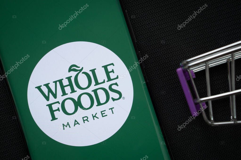Dhaka, Bangladesh- 03 July 2025: A smartphone displaying the Whole Foods Market logo next to a miniature shopping cart on a background