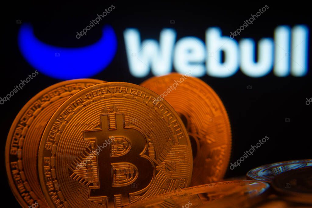 Dhaka, Bangladesh- 03 Sep 2025: Close-up of Bitcoin coins with the webull logo visible on a screen in the background.