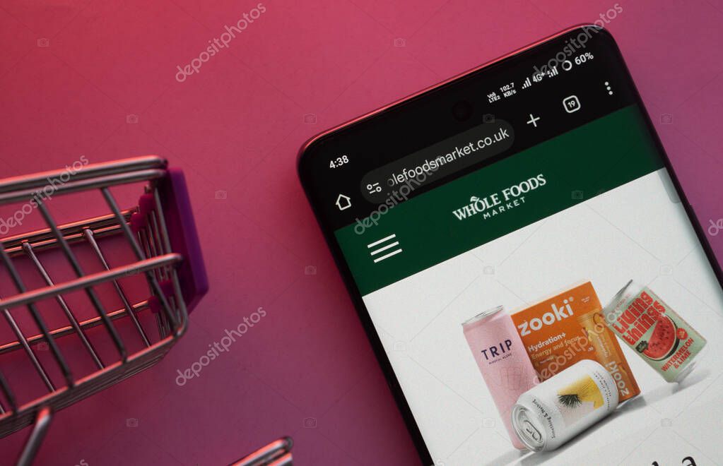 Dhaka, Bangladesh- 23 June 2025: A smartphone displaying the Whole Foods Market website with a shopping cart is shown on a vibrant background.
