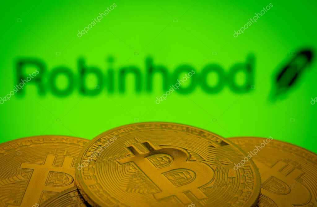 Dhaka, Bangladesh- 20 Sep 2025: Close-up of Bitcoin coins with the Robinhood Markets logo visible on a screen in the background.