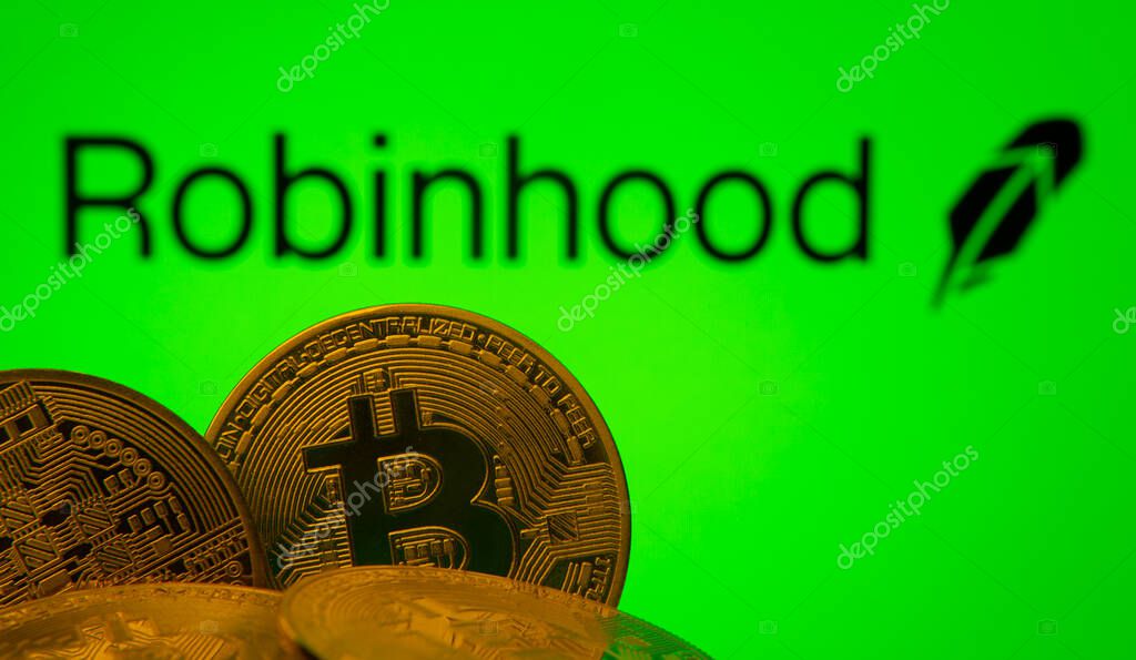 Dhaka, Bangladesh- 20 Sep 2025: Close-up of Bitcoin coins with the Robinhood Markets logo visible on a screen in the background.