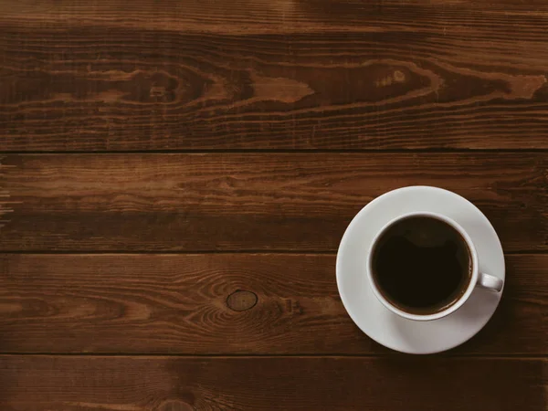 Xícara de café preto em um fundo de madeira marrom. Processamento de autor, efeito de filme, tecla baixa . — Fotografia de Stock