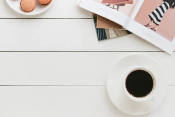 Xícara de café preto em uma mesa de madeira branca com revista de moda. Processamento de autor, efeito de filme . — Fotografia de Stock