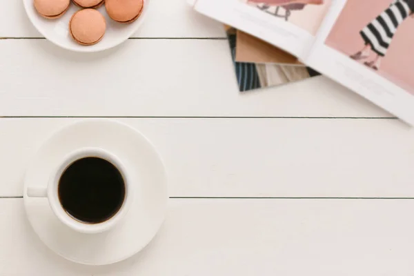 Xícara de café preto em uma mesa de madeira branca com revista de moda e macaroons. Processamento de autor, efeito de filme . — Fotografia de Stock