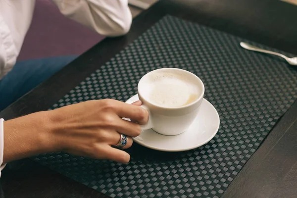 Mulher com belas mãos está bebendo café no café. Cappuccino close-up em copo branco, imagem com efeito de filme e processamento de autor . — Fotografia de Stock