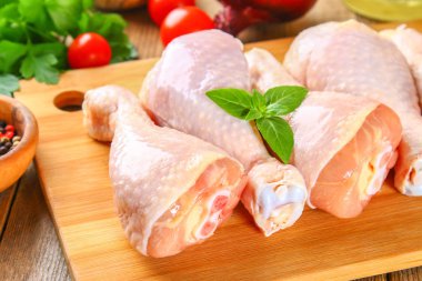 Bir kesme tahtası üzerinde eski bir ahşap masa üzerinde çiğ tavuk budu