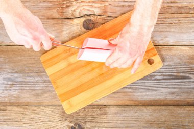 Erkekler ellerini kesti Bolognese sosis kesme tahtası üzerinde eski bir ahşap masa