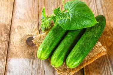 Eski bir ahşap masa üzerinde bir yaprak taze salatalık