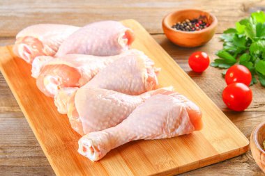 Bir kesme tahtası üzerinde eski bir ahşap masa üzerinde çiğ tavuk budu