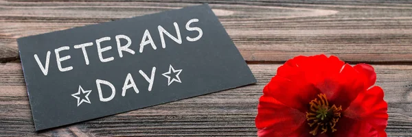 the text thank you veterans written in a chalkboard and red poppy on a rustic wooden background