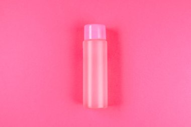Pembe bir şişe, kozmetik, şampuan veya gıda için bir şişe, bir pastel pembe bir içki. Yaz. Üstten görünüm. Düz yatıyordu. Kopya alanı
