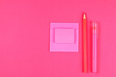 Pembe keçeli kalem, kurşun kalem ve pastel pembe bir arka plan üzerine notlar için sayfaları. Yaz. Üstten görünüm. Düz yatıyordu. Kopya alanı