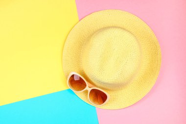 Şapka, güneş gözlüğü, mavi, sarı ve pembe pastel üç renkli arka plan üzerinde