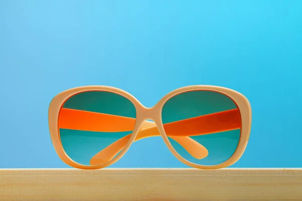Óculos Sol Amarelos Uma Prateleira Madeira Fundo Pastel Azul Minimalismo — Fotografia de Stock