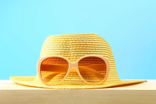 Gafas Sol Sombrero Amarillos Estante Madera Sobre Fondo Azul Pastel — Foto de Stock