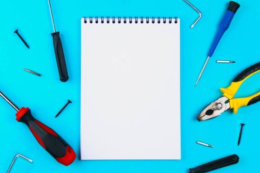 Ev, ev onarım, tadilatta, yenilenen konsepti. Mavi bir ızgara üzerinde onarım araçları kümesi: lay düz iki tornavida ve not defteri, üstten görünüm