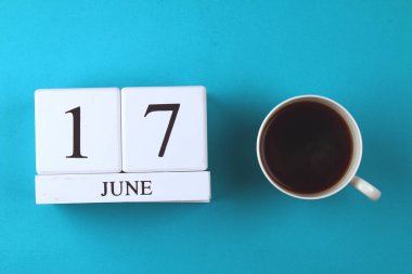 Ahşap bir defter ile 17 Haziran'da bir tarih ve bir kahve kupa pastel mavi bir arka plan üzerinde. Babalar günü