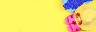 Terlikler, bikini, havlu, şapka ve güneş gözlüğü sarı arka planda. Seyahat, deniz, tatil